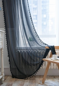 Dettaglio della tenda in pizzo nero con intricati motivi geometrici traforati e nappe eleganti