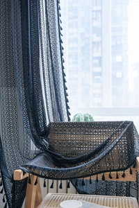 Dettaglio di una tenda in pizzo nero vintage all'uncinetto con nappe e fiori