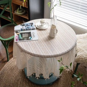 White crochet lace round tablecloth with elegant fringes in a rustic garden setting