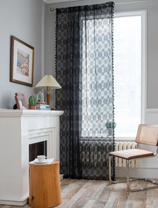 Dettaglio di tenda in pizzo nero con motivi floreali e frange con nappe molto eleganti