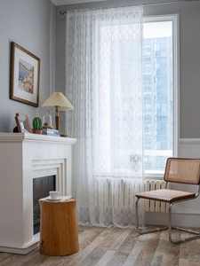 Detail of white crochet lace curtain with retro floral patterns and delicate fringe trim