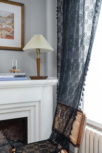 Dettaglio della tenda in pizzo nero con motivo floreale all'uncinetto e nappine decorative