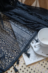 Dettaglio della tenda in pizzo nero all'uncinetto con motivi di rose e nappe