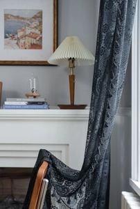 Dettaglio della tenda in pizzo nero con ricamo floreale vintage e piccole nappe sui bordi