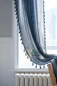 Dettaglio tenda in pizzo nero all'uncinetto con motivi floreali vintage e frange eleganti