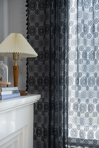 Dettaglio della tenda in pizzo jacquard bianco con eleganti frange e motivo floreale
