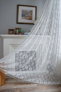 Detailed view of white floral lace crochet curtains with decorative tassel edge finish