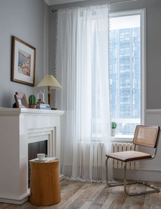 Detail of white semi-transparent lace curtain with vertical stripes and tassel fringe