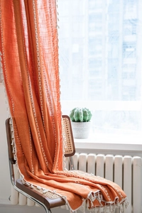 Detail of terracotta cotton linen curtain with white V-shaped embroidery and tassels