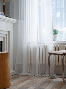 Close-up of white crochet lace curtain featuring floral patterns and delicate fringe trim