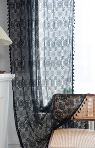 Dettaglio tenda in pizzo nero con ricami floreali traforati e finiture decorative a frange