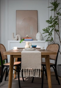 Detailed texture of beige woven table runner featuring decorative handmade side tassels