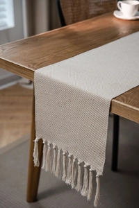 Detail of Nordic geometric table runner with textured weaving and handmade tassels