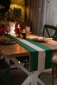Detail of green and beige striped knit table runner with handcrafted woven tassels