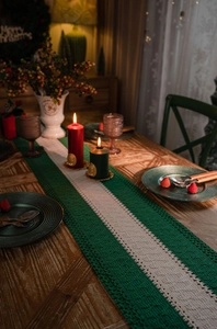 Detail of green and white striped knit table runner with tassels on a rustic wood table