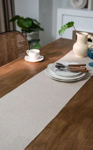 Close-up of beige woven table runner with jacquard texture and natural tassel fringe