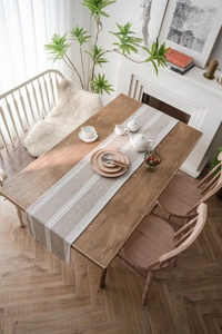 Detail of Nordic table runner featuring beige stitching and elegant white lace borders