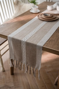 Detail of Nordic table runner with linen texture, woven patterns and handmade tassels
