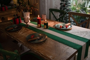 Detailed close-up of green and white striped knit table runner with holiday decor