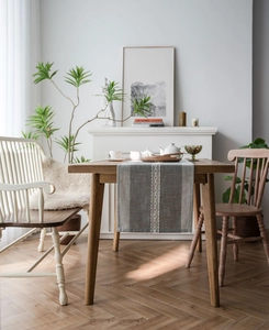 Detailed weave of grey geometric table runner with tassels on solid wood table surface