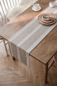 Detailed close-up of Nordic geometric jacquard weave and white tassels on a table runner