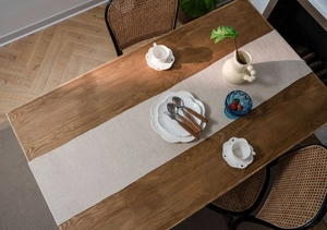 Detail view of woven geometric table runner with textured fabric on wooden table