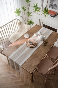 Close-up of Nordic woven table runner with tassels and hollow lace pattern on wood table