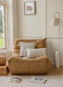 Detail of bohemian cream crochet pillows with tassels on a yellow lounge sofa