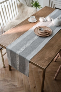 Detail of grey striped cotton linen table runner with white wavy embroidery