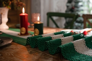 Close-up of forest green and cream crochet table runner with knitted holiday patterns