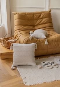 Detail of bohemian cream textured pillow with handmade tassels and woven patterns