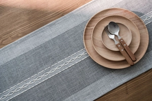 Close-up of Nordic geometric table runner with grey stripes and white cross-stitch detail