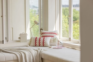 Detail of red geometric embroidery and decorative tassels on beige cushion covers