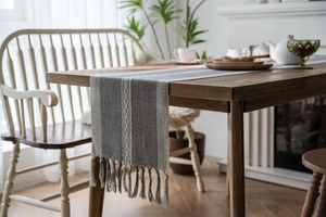 Detail of Nordic grey striped woven table runner with decorative handmade tassels