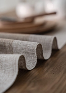 Close-up of oatmeal jacquard table runner with delicate edge stitching and woven texture