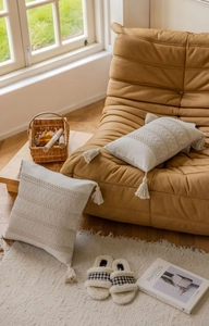 Detail of cream woven throw pillow covers with textured wave knit and cotton tassels