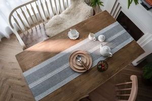 Close-up of blue Nordic table runner with white woven ribbon on wooden table