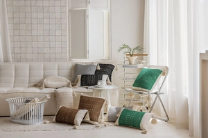 Detail of bohemian jacquard pillow with handmade tassels on a minimalist sofa