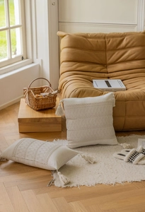 Close-up of bohemian cream crochet throw pillows with geometric patterns and tassels