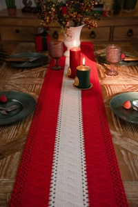 Detail showing red and white knitted table runner with hollow crochet texture on wood table
