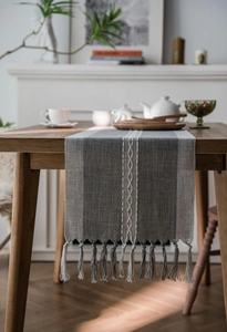 Detailed close-up of Nordic grey jacquard table runner with tassel fringe and woven texture