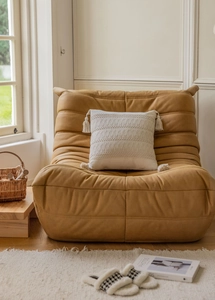 Close-up of beige jacquard pillow with tassels on a tan tufted lounge chair