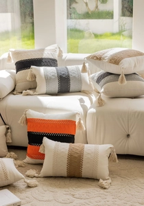 Detail of bohemian jacquard pillow with handmade tassels and woven patterns on sofa