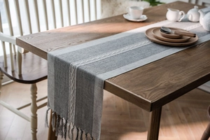 Detail of Nordic jacquard table runner with woven textures and handmade tassel fringe