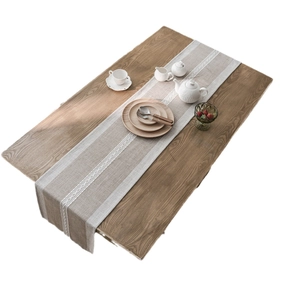 Nordic beige cotton linen table runner with white embroidery on a wooden dining table