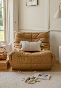 Detail of camel Togo style sofa with pleated fabric and fringed rectangular pillow