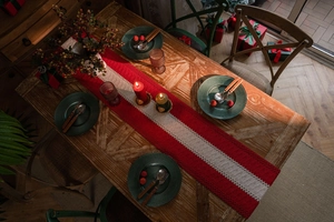Detail of red and white knitted Christmas table runner with tassels and festive decor