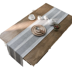 Nordic grey and white striped table runner with white lace edges on a dark wood table