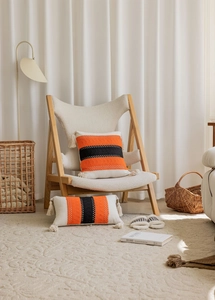 Detail of woven textured pillows featuring bold orange and black stripes with fringe tassels