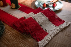 Macro shot of red and cream knitted table runner with fringe and hollow texture details